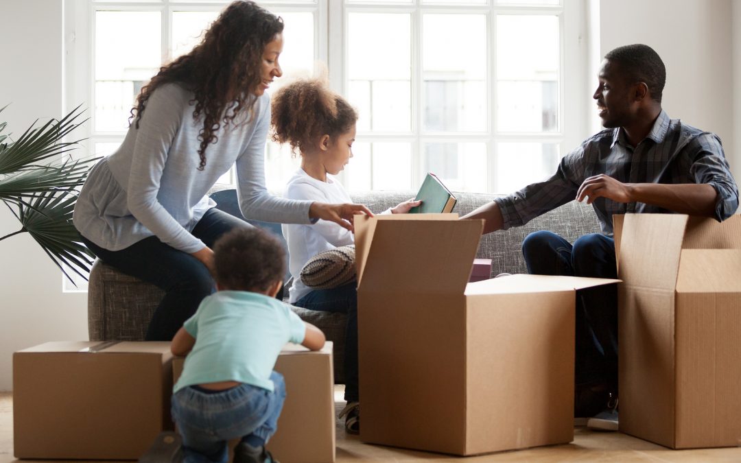 A multi-racial family of four unpacking boxes in their new home.