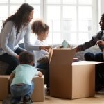 A multi-racial family of four unpacking boxes in their new home.