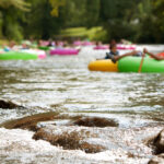 People in color inner tubes floating down a river.