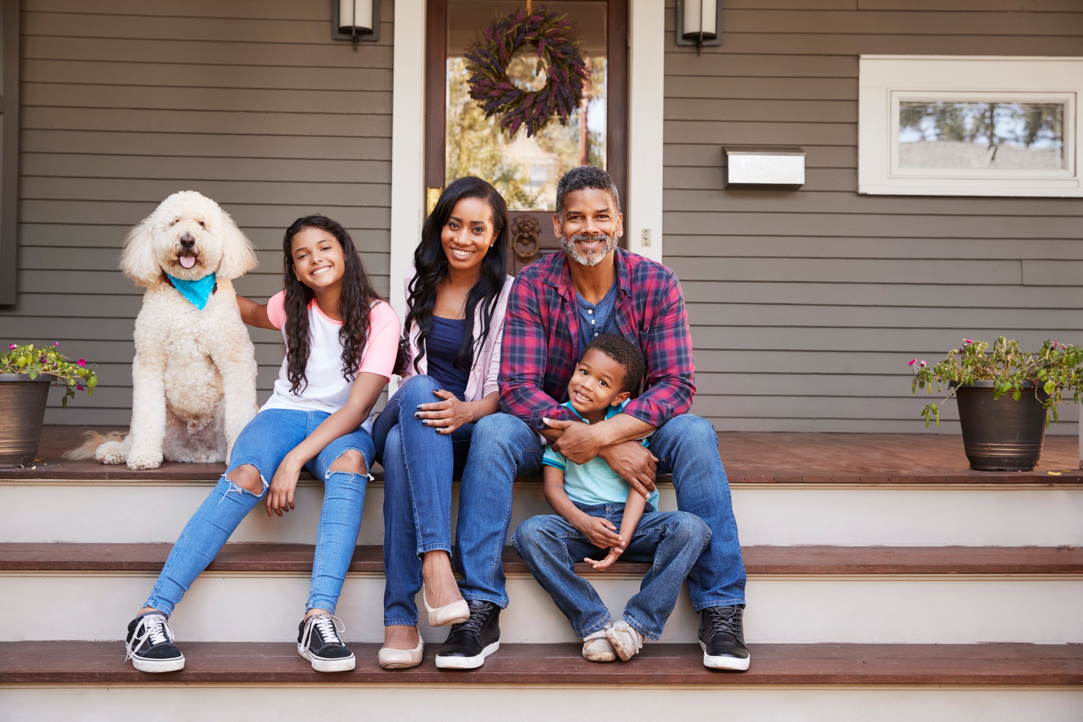 An African-American family and their dog sit on the front porch of their pet-friendly rental home in Bend, Oregon.