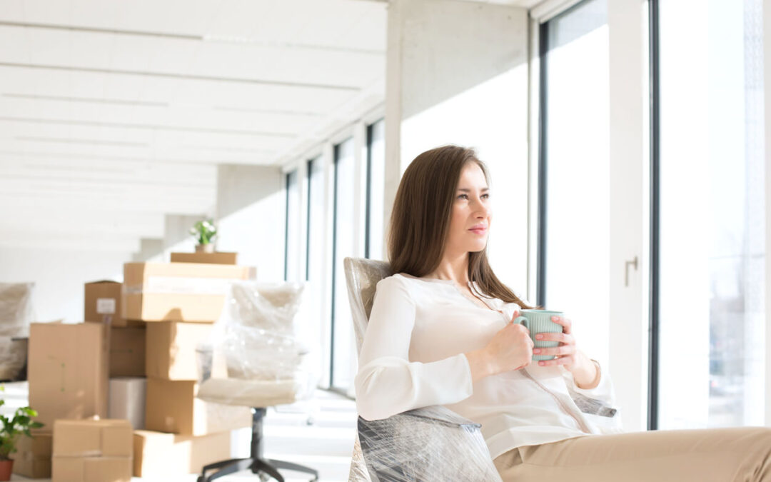 A business woman relaxes in her new office with boxes behind her as part of a corporate relocation to Bend, Oregon.